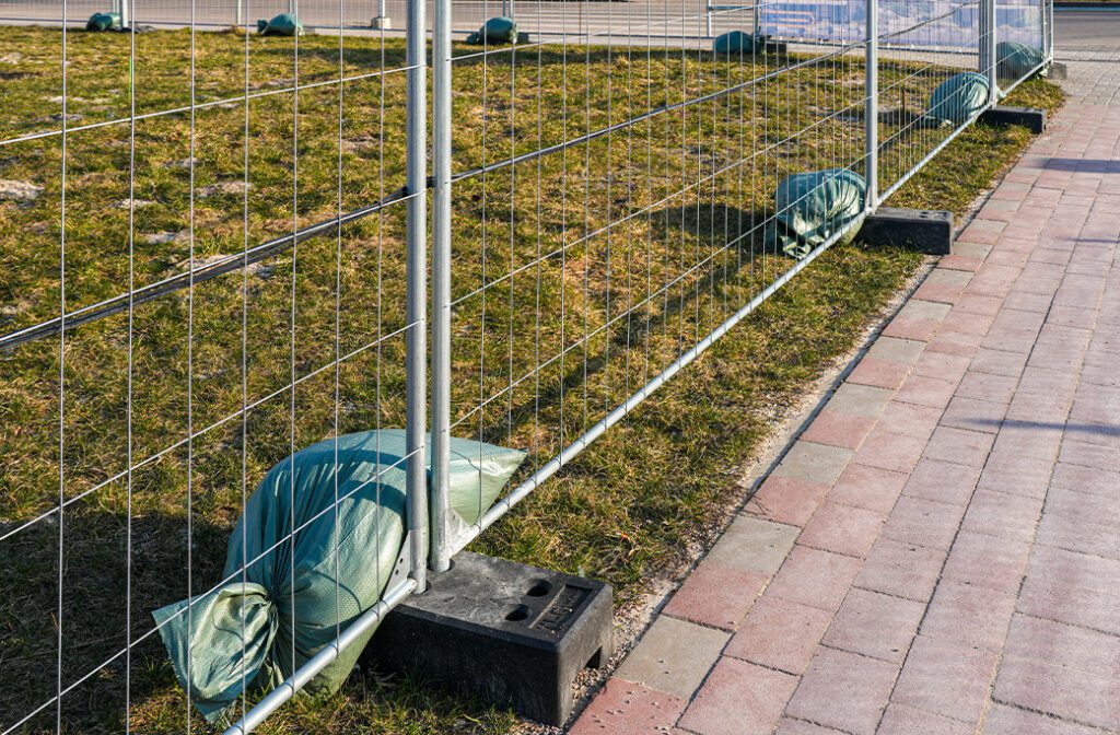 Temporary fence panel supported by a rubber footing on concrete